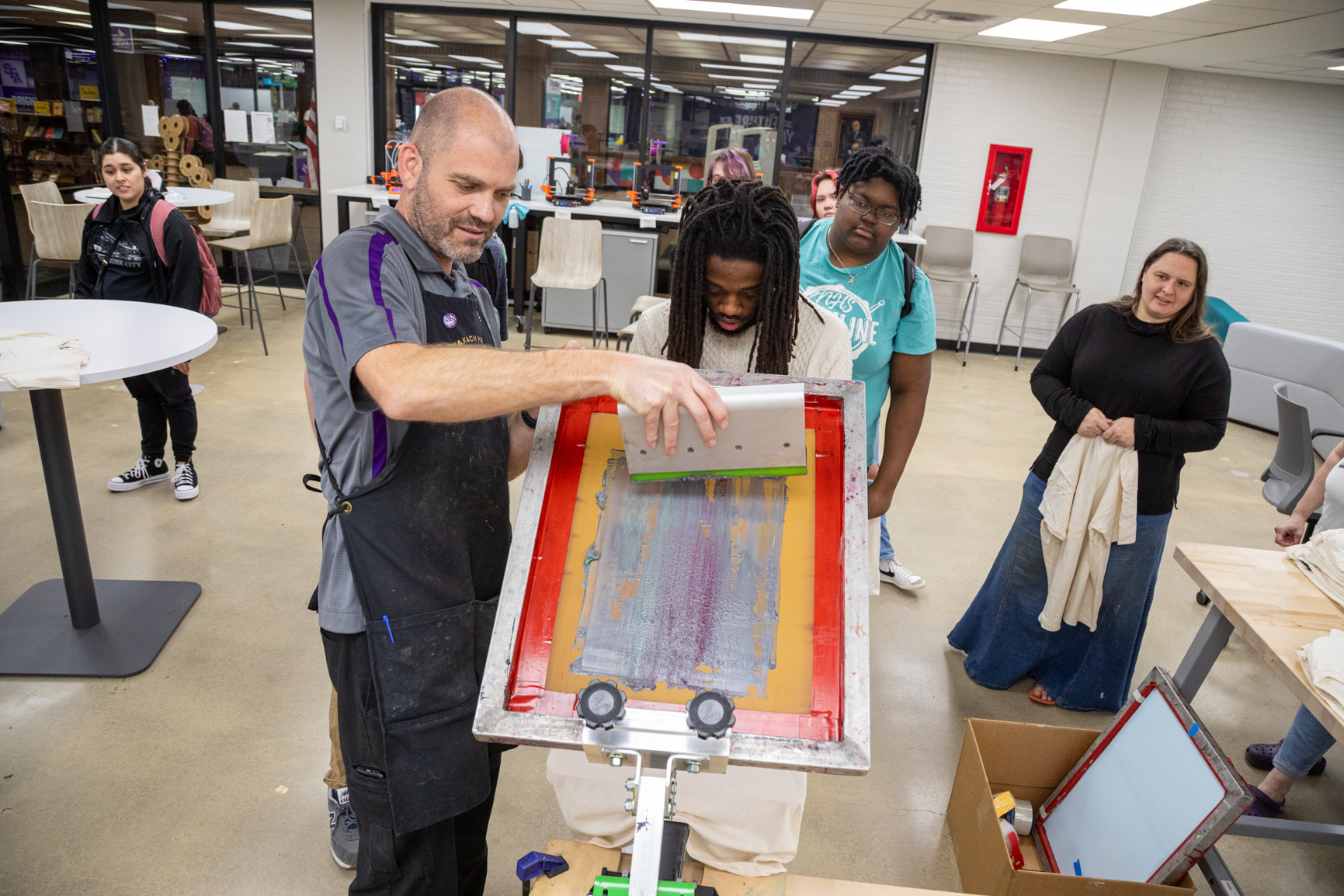 Professor Neal Cox demonstrates how to screen print on a T-shirt during a makerspace event inside the Ralph W. Steen Library. Series produced for Stephen F. Austin State University marketing material and social media, 2025.